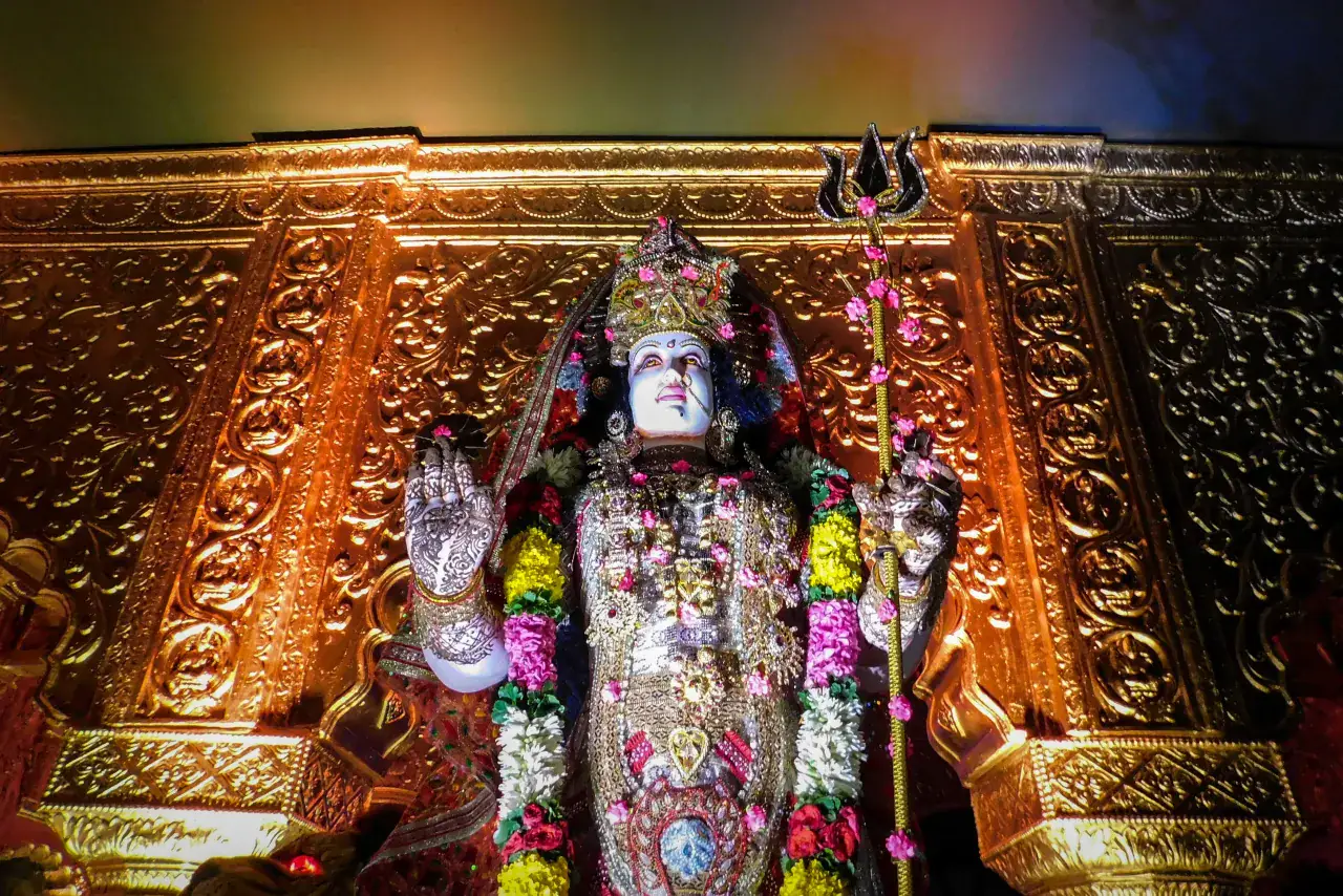 A flower-adorned image of Goddess Durga in a temple setting