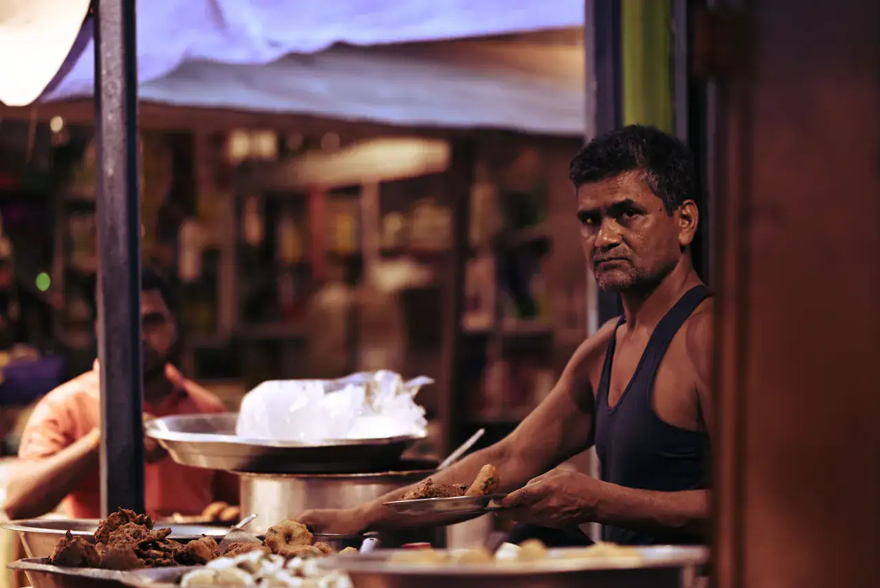 A street-food vendor preparing Indian snacks at night