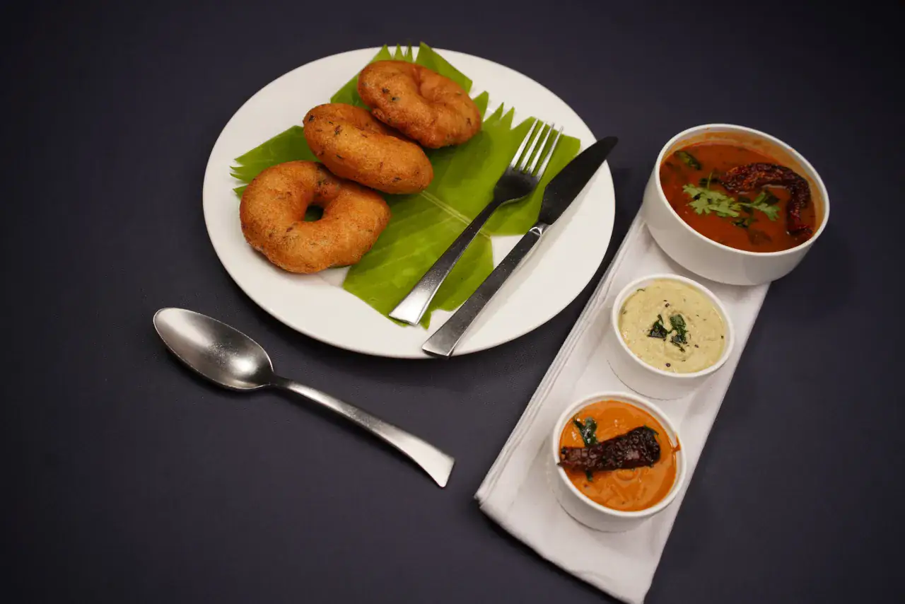 Vadai served with sambar and chutneys on a banana leaf